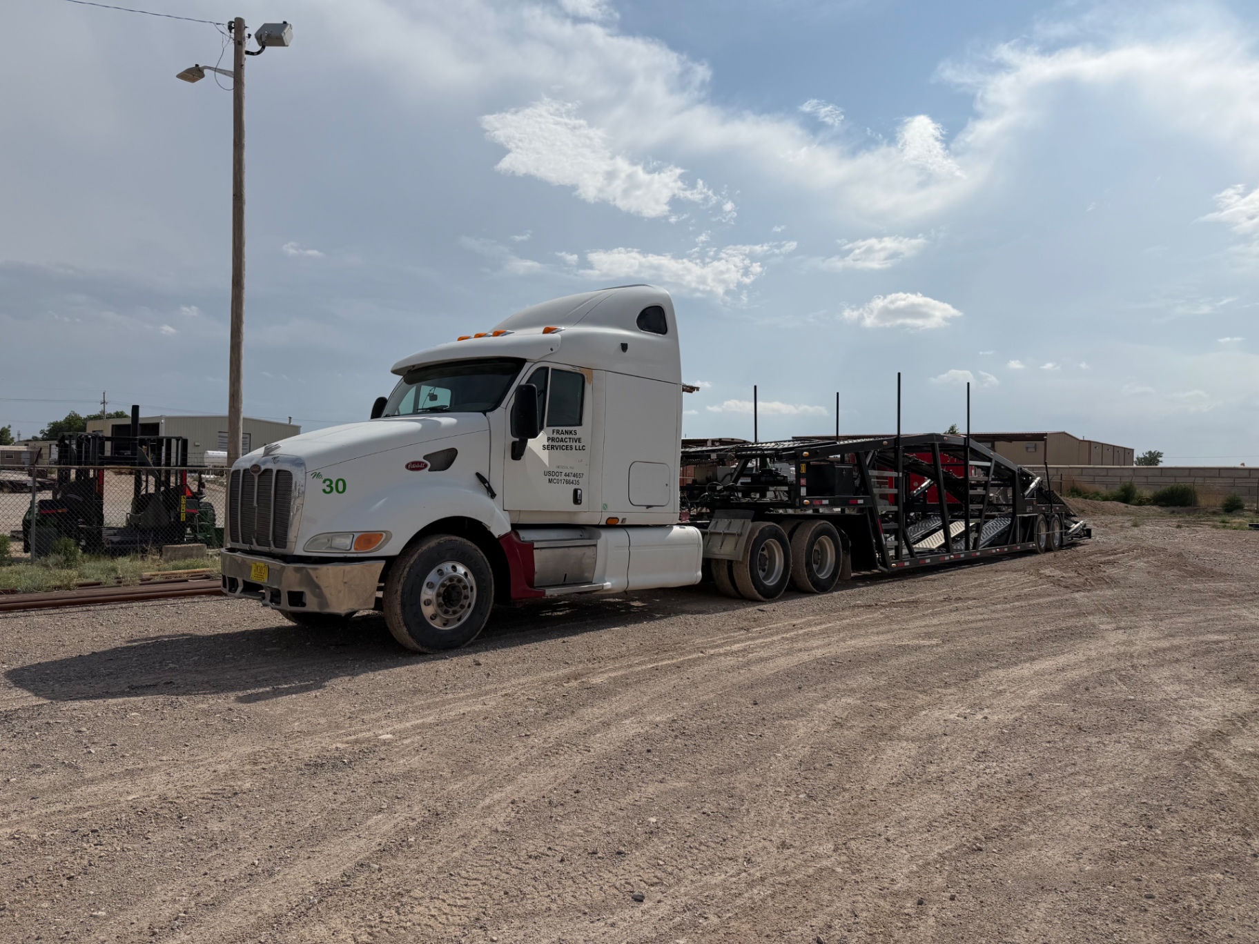 Frank's white semi truck and car-hauling trailer parked in a yard